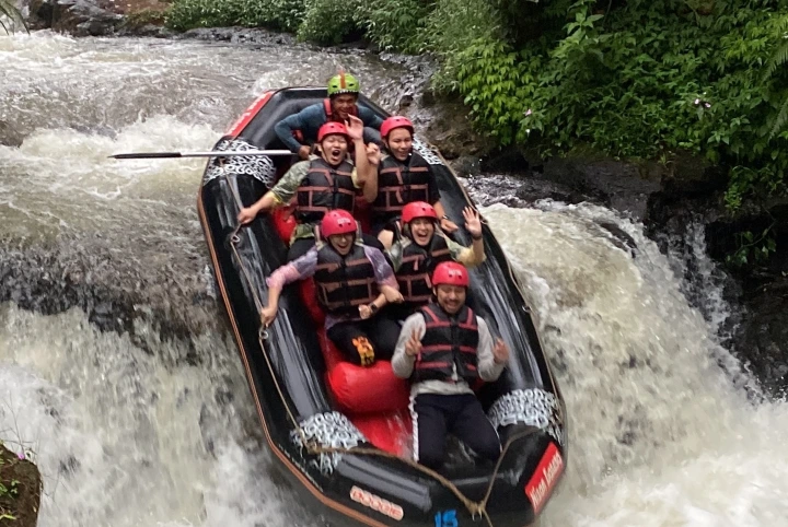 Group of six people rafting down a river.